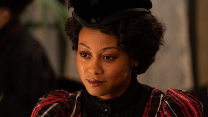 A dark-skinned Black woman with curly hair and a Black hat (Shanice Banton as Violet Hart)